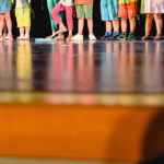 Children on a stage to represent a work in their school, unrecognizable, only their feet with copy space.